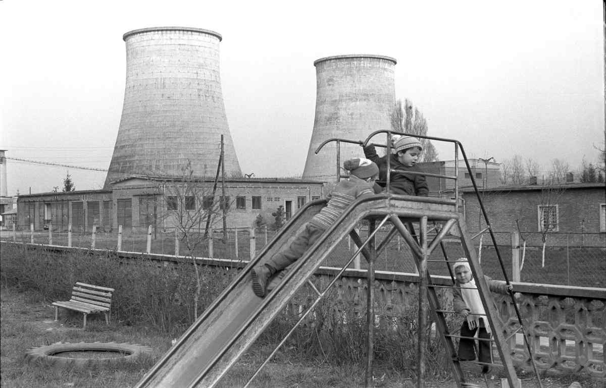 Children playing at a playground in front of a factory building