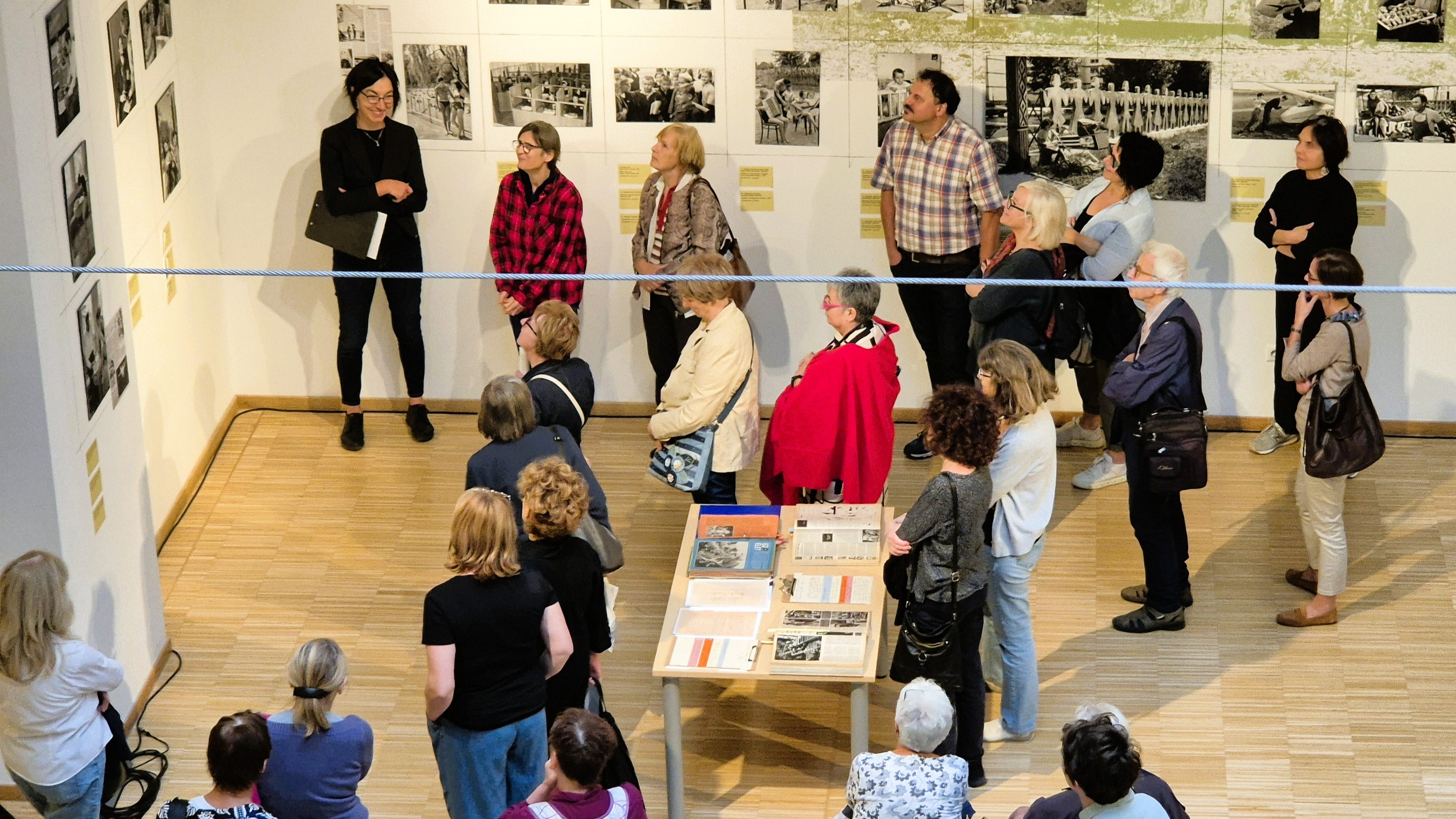 Guy holding a piece of a watermelon with his knife. In the background a girl is watching