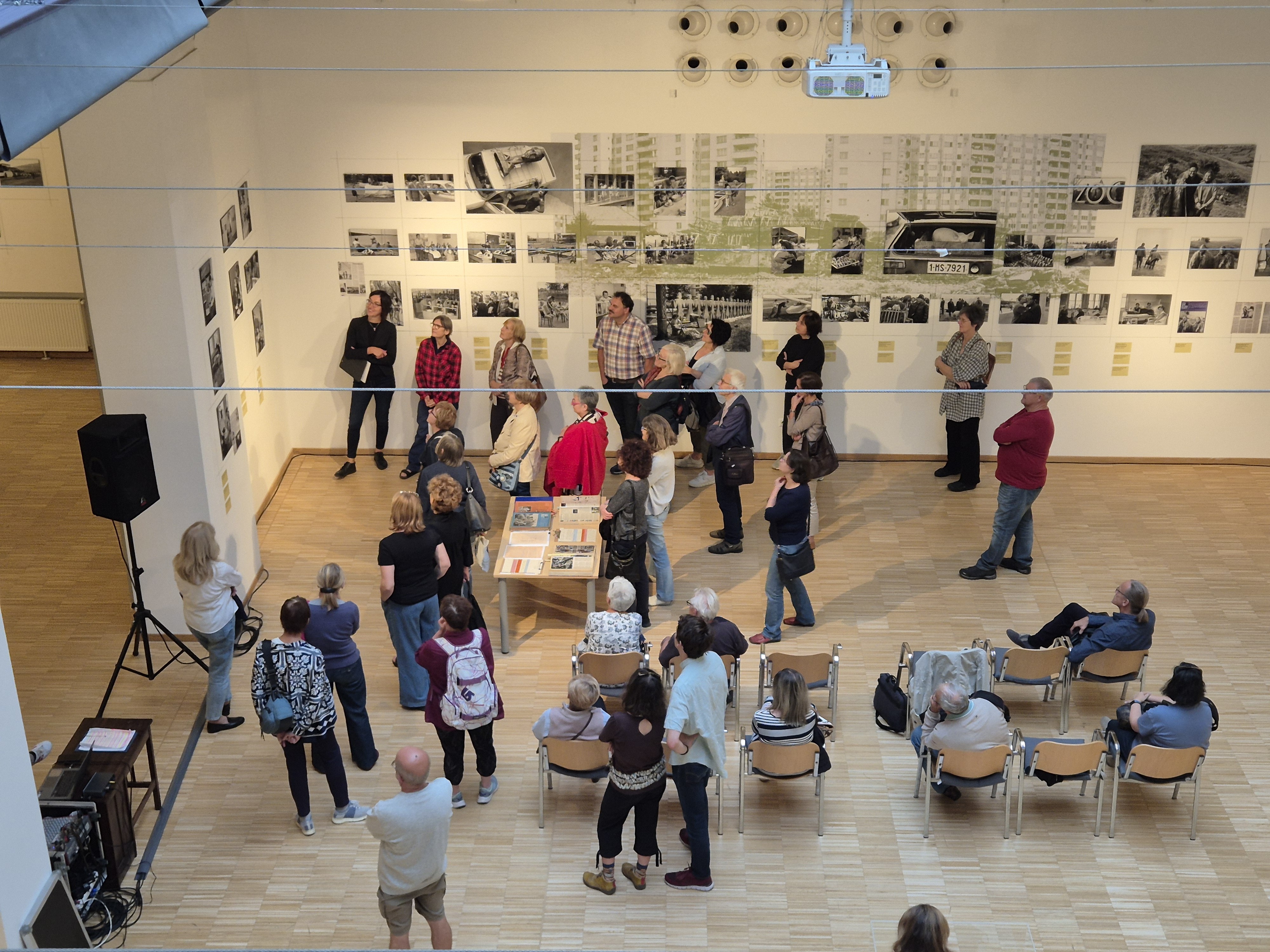 Guy holding a piece of a watermelon with his knife. In the background a girl is watching
